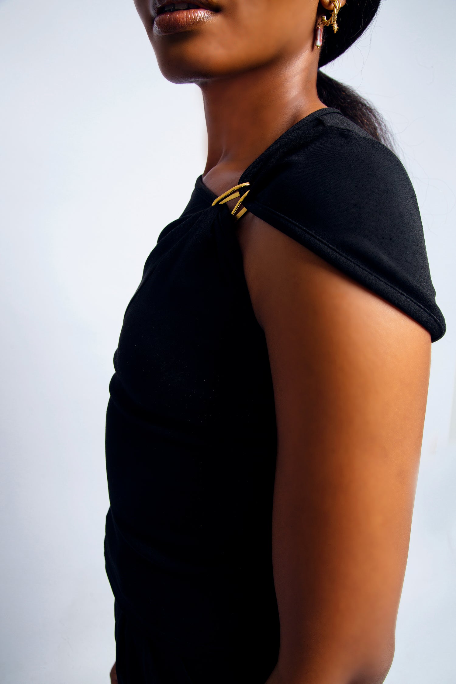 Black asymmetric sleeve top with gold clasp detail